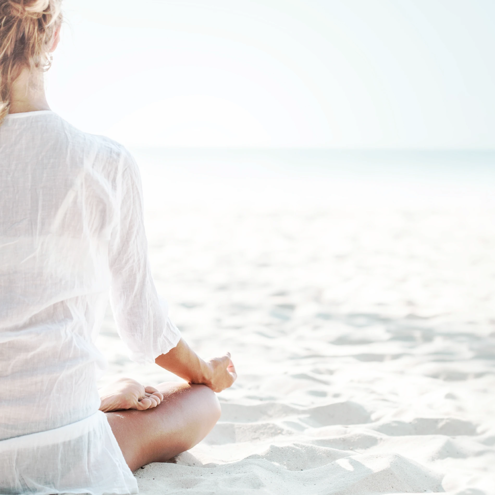 Photo of a retired woman meditating on a quiet beach.